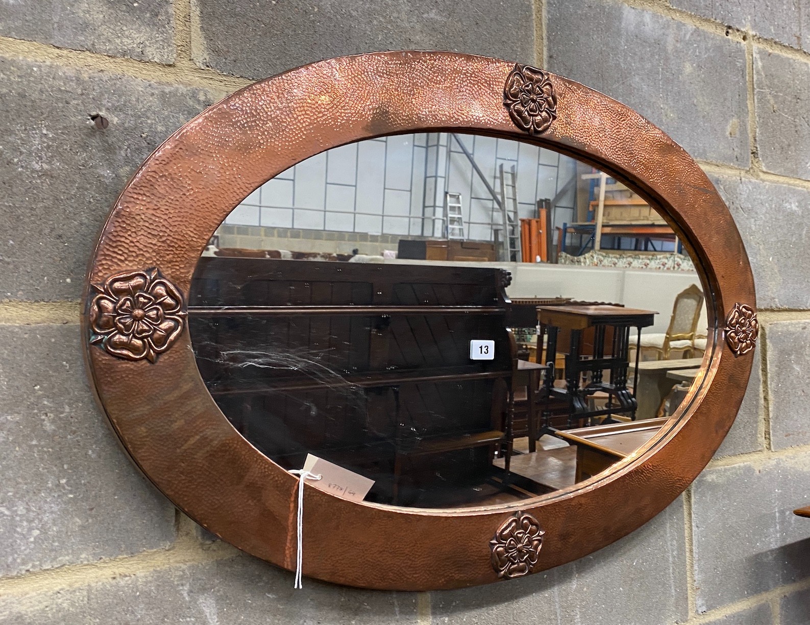 An Arts & Crafts embossed copper oval wall mirror, width 92cm, height 60cm